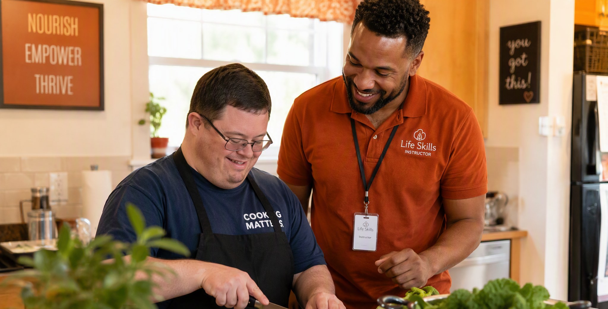 An ILS instructor coaching a smiling adult while cooking together in a home kitchen